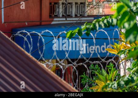 Bobines de fil de rasoir sur le mur d'un complexe de maison à Guazacapan, Guatemala Banque D'Images