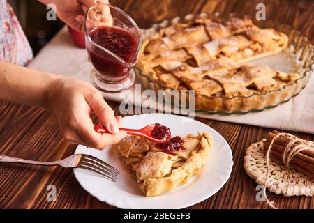 Tranche de tarte aux pommes sur une plaque colorée avec fourche et confiture. Vue rapprochée Banque D'Images