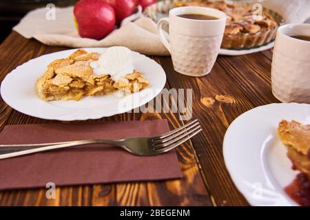 Tarte aux pommes maison savoureuse, tranche avec glace. Pommes. Plaque, serviette en lin fond de bois tasse de thé Banque D'Images