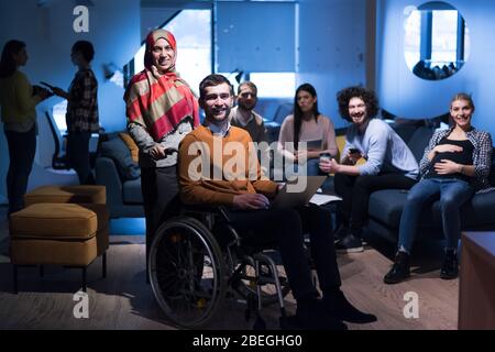 Jeune homme handicapé avec collègues travaillant au bureau. Exécution dans un espace de travail commun. Personnel de bureau travaillant ensemble. Regarder dans l'appareil photo Banque D'Images
