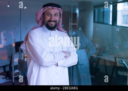 L'homme d'affaires arabe moderne dans la tradition s'adapte à la position et à la réflexion sur de nouveaux projets et investissements dans l'avenir. Sourire dans l'appareil photo. Banque D'Images