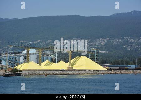 Vues industrielles des piles de granulés de soufre utilisés dans les engrais vues d'un voyage en bateau autour du port de Vancouver, Canada. Banque D'Images