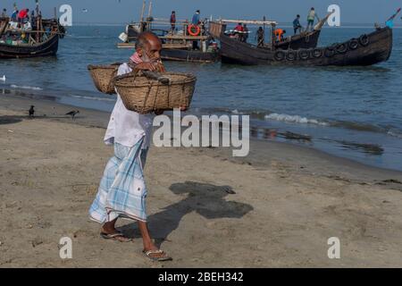 Homme âgé transportant des paniers de poisson vides dans un village de pêche au nord de Cox's Bazar Banque D'Images