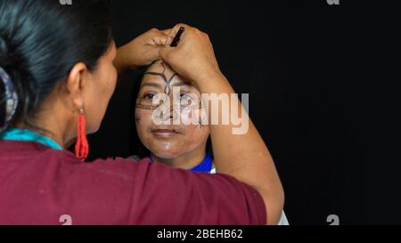 Lago Agrio, Sucumbios / Equateur - 29 février 2020: Femme du groupe ethnique Quichua de l'Amazonie équatorienne qui demande la composition au visage de sa sœur Banque D'Images