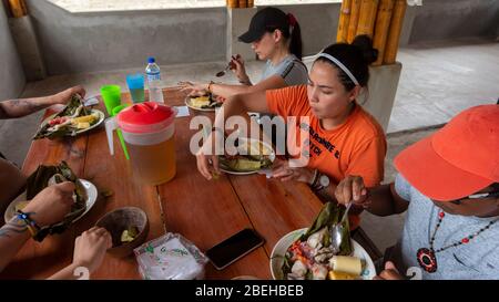 Groupe de touristes mangeant des maitos de poisson dans la communauté du millénaire Cofan Dureno Banque D'Images