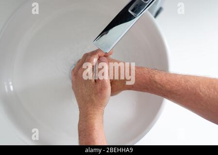 L'homme aux mains froissées se lave les mains pendant l'éclosion de Covid-19. Banque D'Images