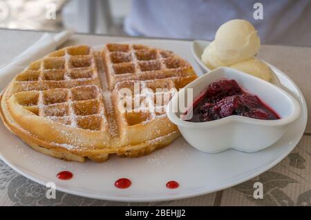 Gaufres belges recouvertes de poudre de sucre servies avec des pelles à glace à la vanille et de la confiture de baies rouges. Style de la nourriture du petit déjeuner Banque D'Images