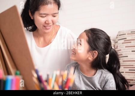 La mère et la fille partagent leurs vacances. Petite fille asiatique fraiseuse avec maman. Enfants apprentissage de la peinture avec parent. Banque D'Images