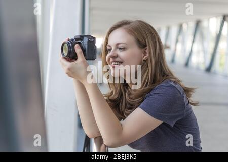 Jeune femme caucasienne photographe fille tenant un appareil photo numérique dans les mains, prenant une photo ou une vidéo Banque D'Images