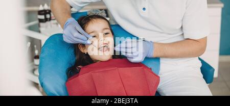 Caucasienne fille avec bouche ouverte ayant un examen dentaire chez le dentiste pédiatrique Banque D'Images