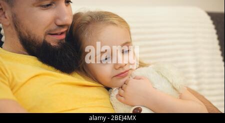 Père barbu et sa fille allongé au lit avec un ours et regardant quelque chose Banque D'Images