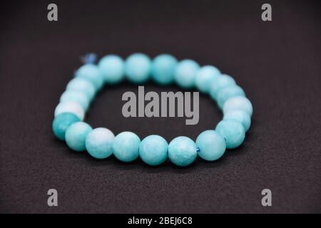 Bracelet fait maison de perles de pierre semi-précieuses bleu naturel sur fond noir Banque D'Images