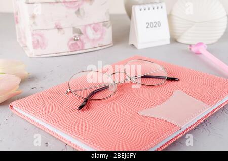Lieu de travail féminin avec tulipes, lunettes et carnet. Banque D'Images