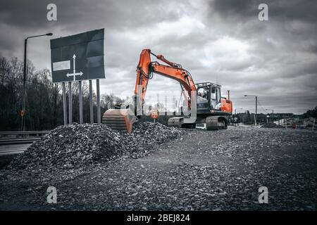 Pelle hydraulique orange sur le chantier de construction de routes. Banque D'Images