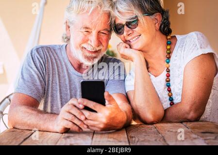 Heureux beau couple senior faire un appel téléphonique avec un appareil moderne de technologie en ligne - les personnes à la retraite avec courage et pour toujours avec amour et amis Banque D'Images