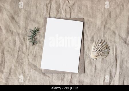 Marine d'été, papeterie de mariage, maquette de bureau scène. Carte vierge en papier de salutation, enveloppe d'artisanat, coquillages et branche d'herbes romarin. Beige Banque D'Images