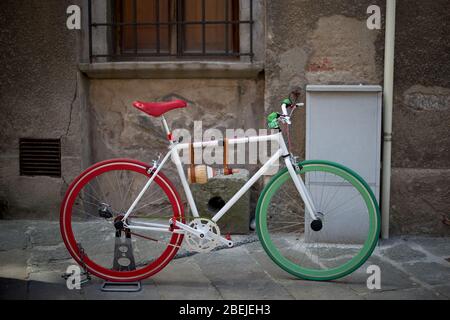 Vélo coloré - rouge et vert, devant la façade d'une ancienne maison dans une rue vide fond. Banque D'Images