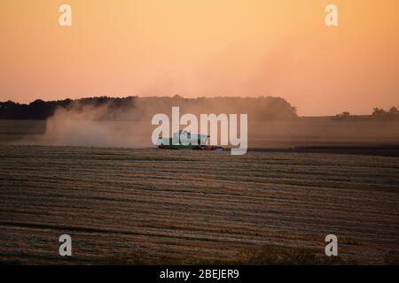 Machine de récolteuse travaillant dans le champ au coucher du soleil. Banque D'Images