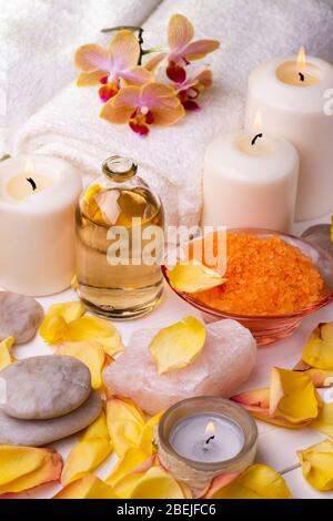 Centre de bien-être. Composition avec sels de bain aromatisés à l'orange, flacon en verre transparent avec huile essentielle parfumée, serviettes blanches, pétales de rose et cand Banque D'Images