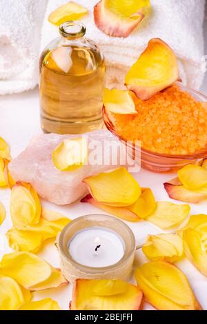 Centre de bien-être. Composition avec sels de bain aromatisés à l'orange, flacon en verre transparent avec huile essentielle parfumée, serviettes blanches, pétales de rose et cand Banque D'Images