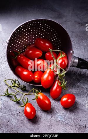 tomates fraîches et mûres dans la vieille passoire sur un fond rustique gris Banque D'Images