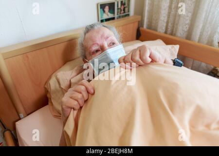Une vieille femme se trouve dans son lit avec un masque facial Banque D'Images