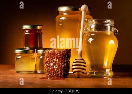 Divers types de miel dans des pots en verre avec ladle et nid d'abeilles. Toujours la vie Banque D'Images