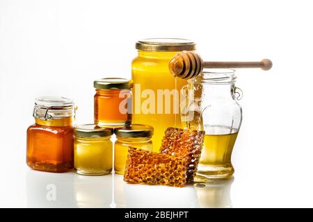 Divers types de miel dans des pots en verre avec ladle et nid d'abeilles. Fond blanc Banque D'Images