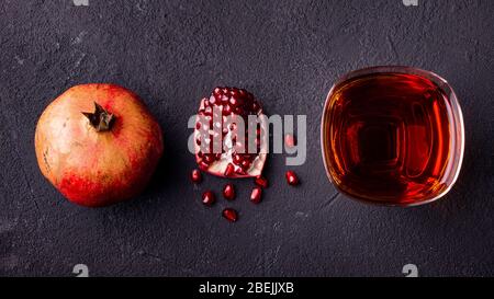verre avec jus de grenade et graines de grenade sur fond sombre et rugueux Banque D'Images