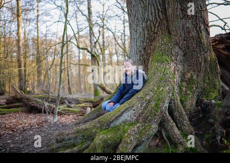 une fille est assise sur le tronc d'un grand arbre Banque D'Images