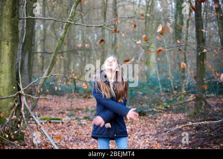 une fille se tient dans la forêt et jette les feuilles dans l'air Banque D'Images