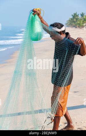 Pêcheur sur la belle plage de Marari en début de matinée avec un filet de coulage à main verte - Mararikulam, Alapuzha District, Kerala, Inde Banque D'Images