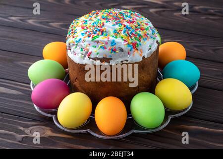 Gâteau de Pâques et œufs colorés peints sur des panneaux en bois sombre. Carte cadeau Paschal. Contexte alimentaire Banque D'Images