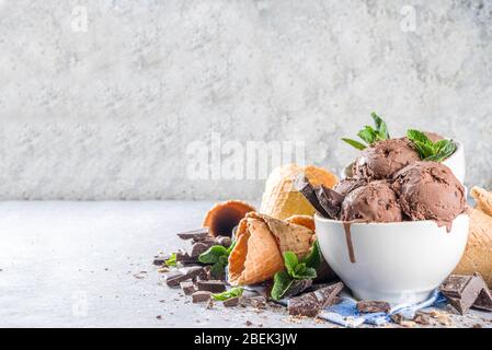 Glace au chocolat maison avec morceaux et copeaux de chocolat, et cônes de crème glacée. Dans de petits bols blancs sur un espace de copie de table en pierre grise blanche Banque D'Images