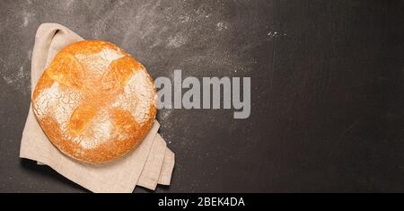 Un petit pain de pain fraîchement cuit sur fond noir. Le concept de la nourriture minimalisme. Mise en page à plat Banque D'Images