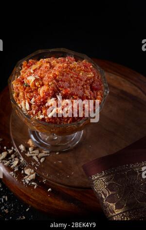 Gajar ka halwa gardait dans un bol à côté d'un chiffon et de pistaches écrasées. Banque D'Images