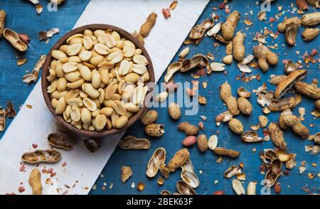 Arachides simples gardées dans un bol en bois avec des coquilles fissurées. Banque D'Images