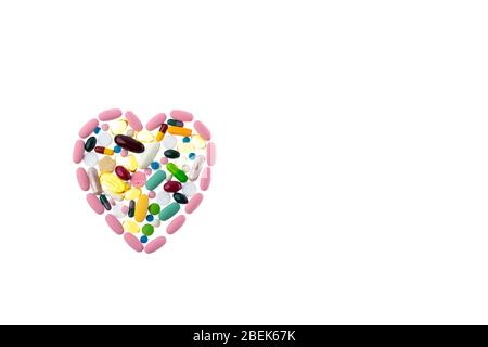 Pilules multicolores en forme de coeur sur un fond blanc isolé. Dose quotidienne de vitamines. Forme du coeur en comprimés, concept de traitement et Banque D'Images