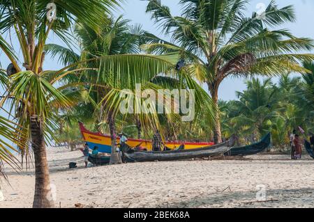 Les familles se détendant à côté de leurs bateaux de pêche en bois dans le petit village de pêcheurs de Marari Beach, Mararikulam, Alapuzha District, Kerala, Inde Banque D'Images