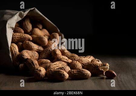 Arachides rôties sortant d'un sac en papier marron. Banque D'Images