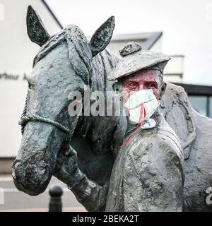 Irvine, Royaume-Uni. 14 avril 2020. La statue emblématique du carter et de son cheval Clydesdale au port d'Irvine représente les connexions nationales et internationales de la ville et sa résilience aux difficultés. Maintenant quelqu'un avec un sens de l'humour a mis un masque PPE sur le carter pour empêcher la contagion de Covid 19, peint son visage et a laissé une pierre peinte sur son épaule remerciant le NHS. Crédit: Findlay/Alay Live News Banque D'Images