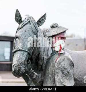 Irvine, Royaume-Uni. 14 avril 2020. La statue emblématique du carter et de son cheval Clydesdale au port d'Irvine représente les connexions nationales et internationales de la ville et sa résilience aux difficultés. Maintenant quelqu'un avec un sens de l'humour a mis un masque PPE sur le carter pour empêcher la contagion de Covid 19, peint son visage et a laissé une pierre peinte sur son épaule remerciant le NHS. Crédit: Findlay/Alay Live News Banque D'Images