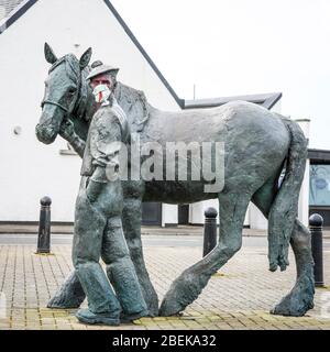 Irvine, Royaume-Uni. 14 avril 2020. La statue emblématique du carter et de son cheval Clydesdale au port d'Irvine représente les connexions nationales et internationales de la ville et sa résilience aux difficultés. Maintenant quelqu'un avec un sens de l'humour a mis un masque PPE sur le carter pour empêcher la contagion de Covid 19, peint son visage et a laissé une pierre peinte sur son épaule remerciant le NHS. Crédit: Findlay/Alay Live News Banque D'Images