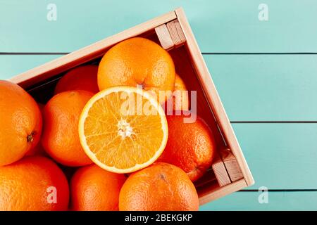 Oranges fraîches dans une boîte en bois ou une caisse sur une table en bois bleu. Vue de dessus. Banque D'Images