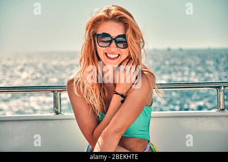 Une jeune fille sur le pont d'un yacht en mer. Elle porte un maillot de bain. Elle est heureuse. Banque D'Images