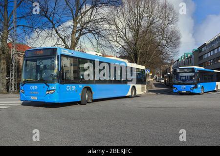 Les bus de Scania cityWide LE et VDL Citea HSL longent la rue le long d'une journée ensoleillée de printemps. Helsinki, Finlande. 17 mars 2020. Banque D'Images