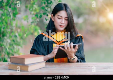 Les jeunes femmes asiatiques de charme célèbrent son diplôme après avoir obtenu un certificat de diplôme le jour du début. Banque D'Images