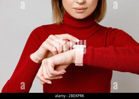 Photo courte de la femme touchant, en plaçant ou en utilisant sa montre intelligente sur son poignet, en vérifiant le temps, la santé et le pouls sur le col de cygne rouge. Banque D'Images