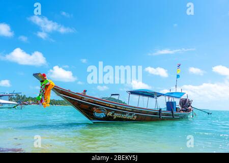 Bateau à queue de logail thaïlandais avec décorations sur l'arc. Bateau amarré au large de la rive sablonneuse. Paysage tropical Banque D'Images