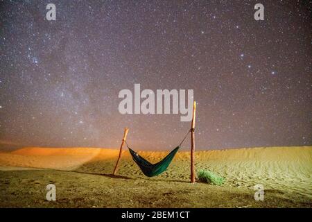 Hamac vert solitaire à côté des dunes sur le désert du Sahara avec un ciel étoilé au-dessus, Maroc Banque D'Images